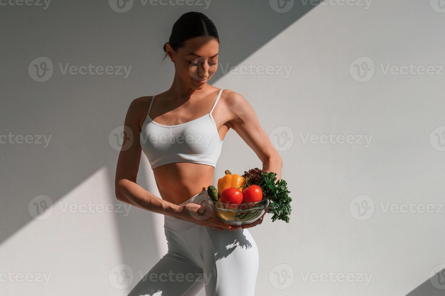 Holding, vegetables and, fruits. Young caucasian woman with slim body shape is indoors in the studio photo