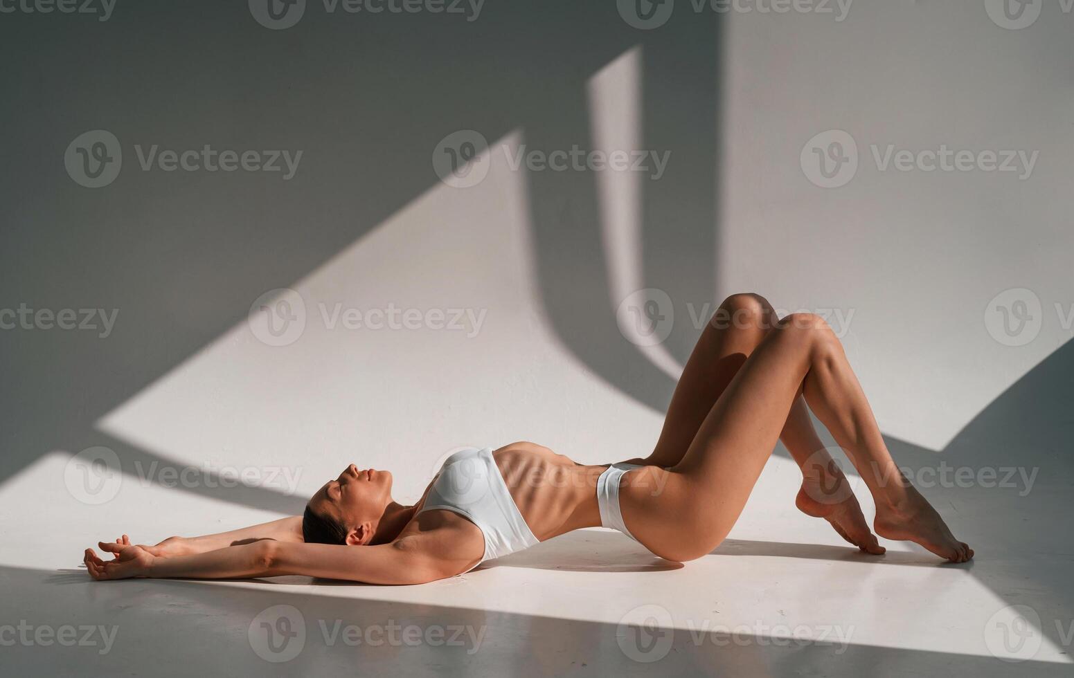 Resting, on, the floor. Young caucasian woman with slim body shape is indoors in the studio photo