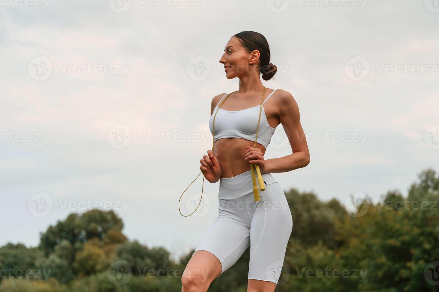 Holding jumping, rope. Young caucasian woman with slim body shape is in the fitness clothes outdoors photo