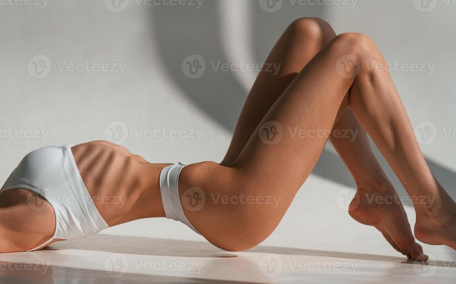 On, the floor. Close ,up view. Young caucasian woman with slim body shape is indoors in the studio photo