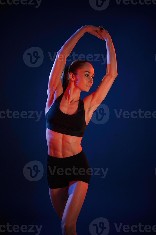 Stretching ,the hands.. Beautiful muscular woman is indoors in the studio with neon lighting photo
