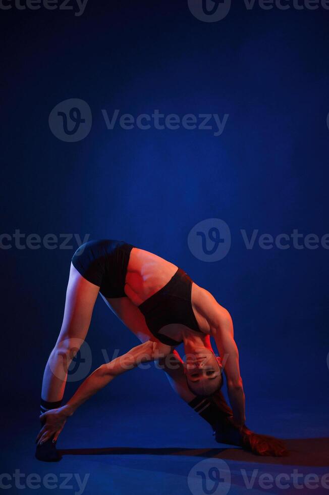 In studio with, red and blue neon lighting. Beautiful muscular woman is indoors photo