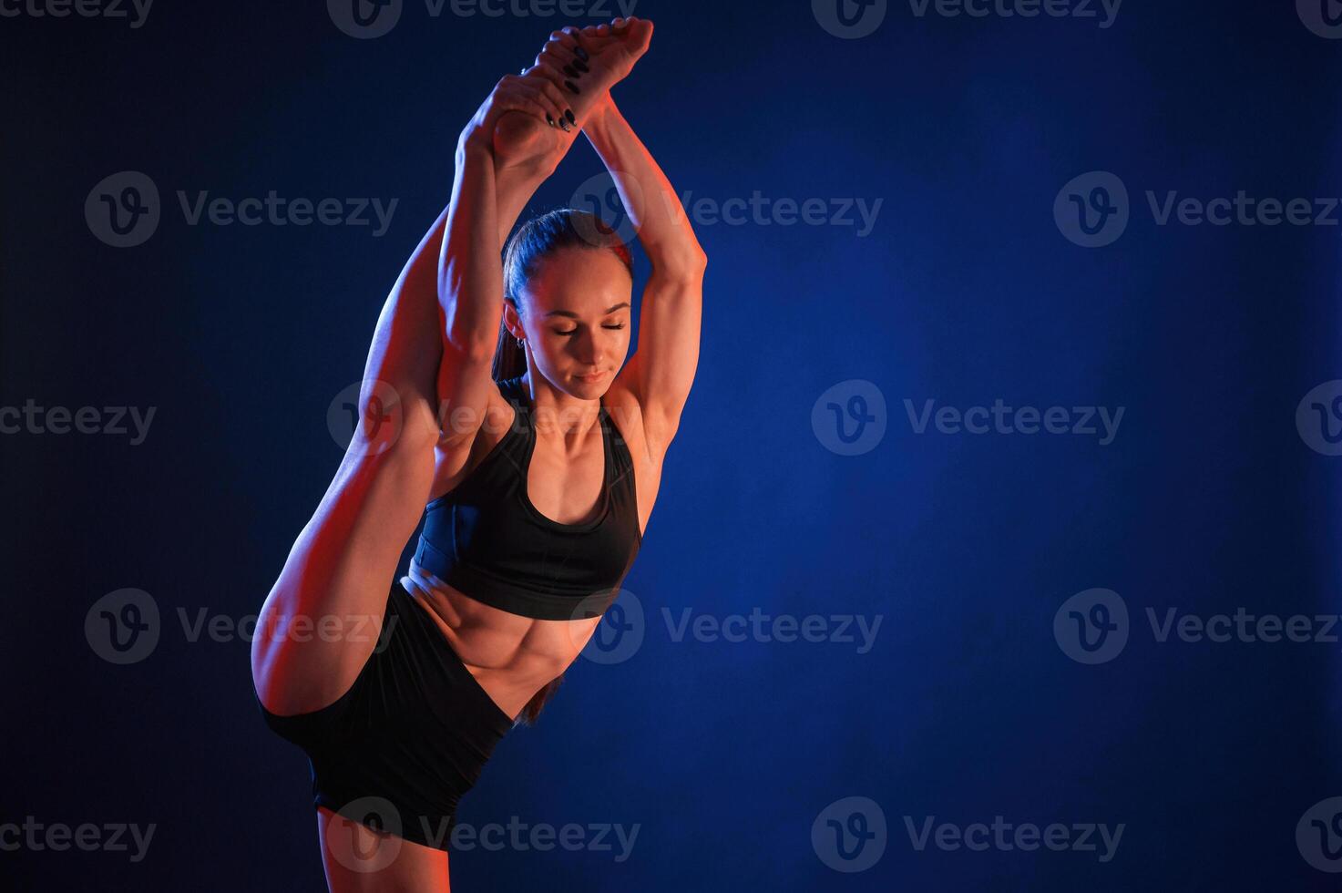 Fitness, exercises. Beautiful muscular woman is indoors in the studio with neon lighting photo