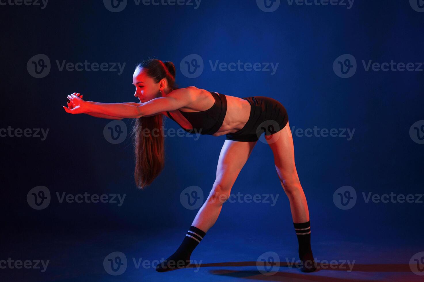 Doing sportive, exerises., Beautiful muscular woman is indoors in the studio with neon lighting photo