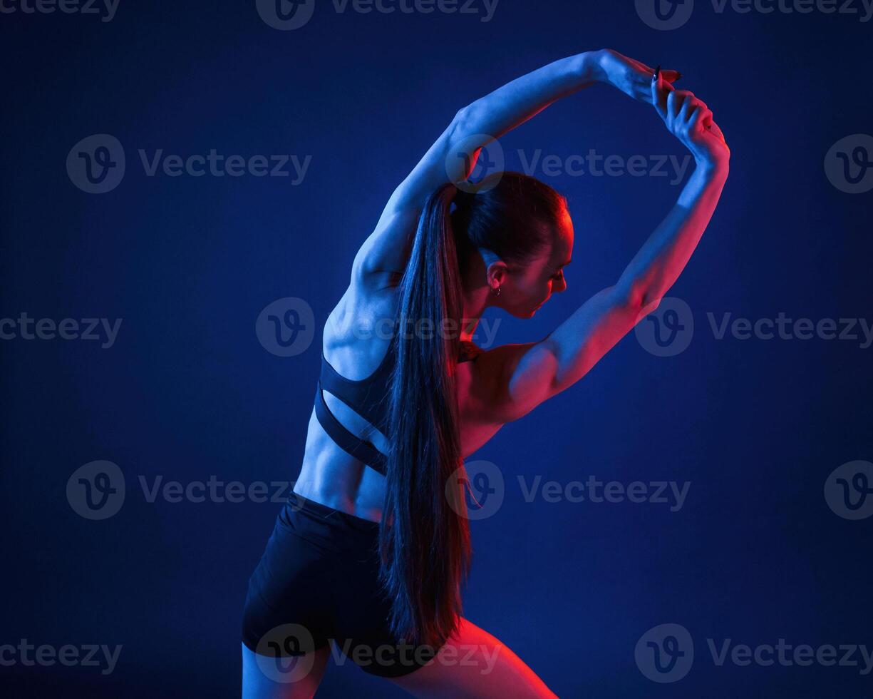 Beautiful muscular woman, is indoors in the studio with neon lighting photo