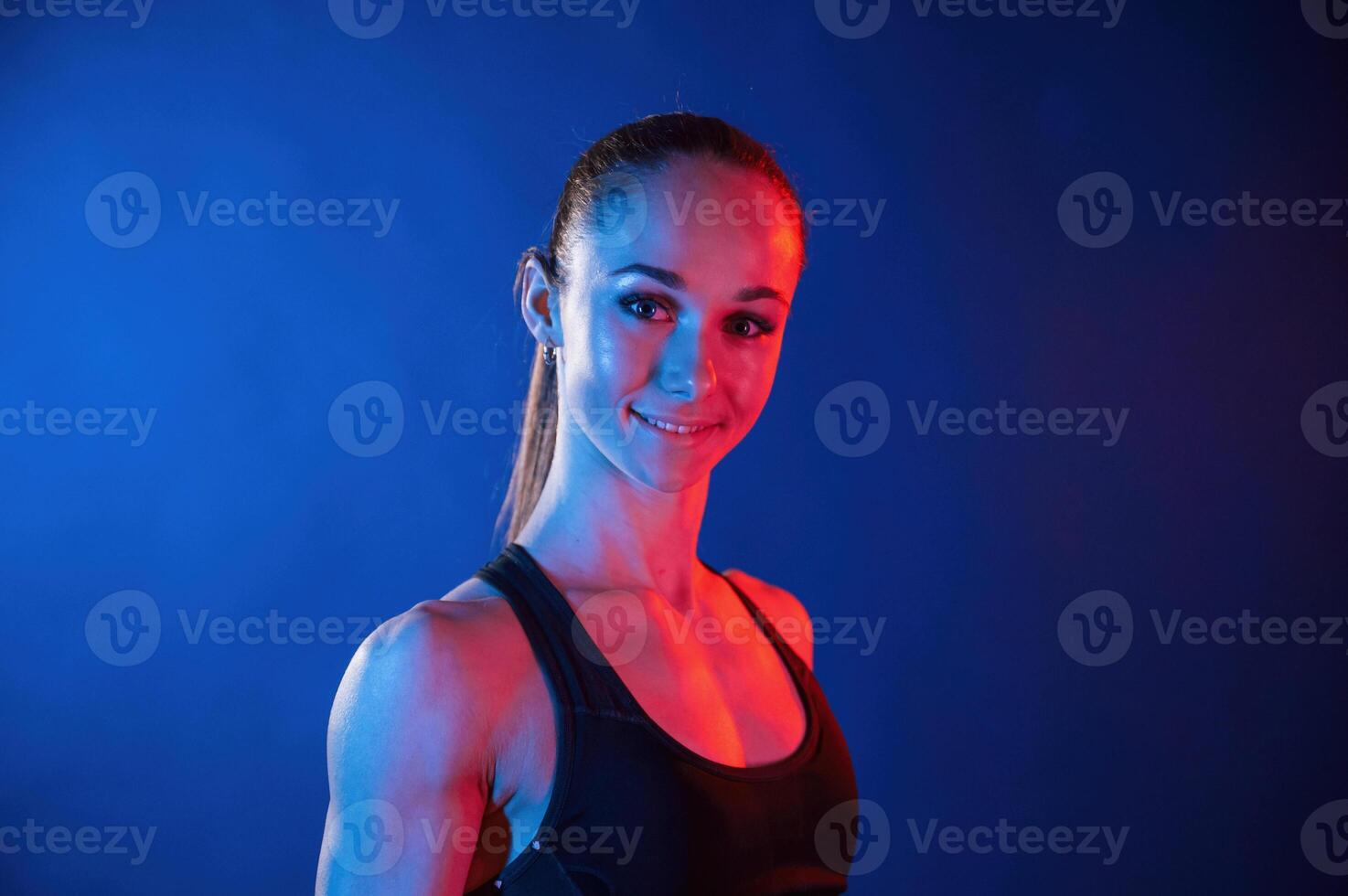 Portrait of beautiful muscular woman that is indoors in the studio with neon lighting photo