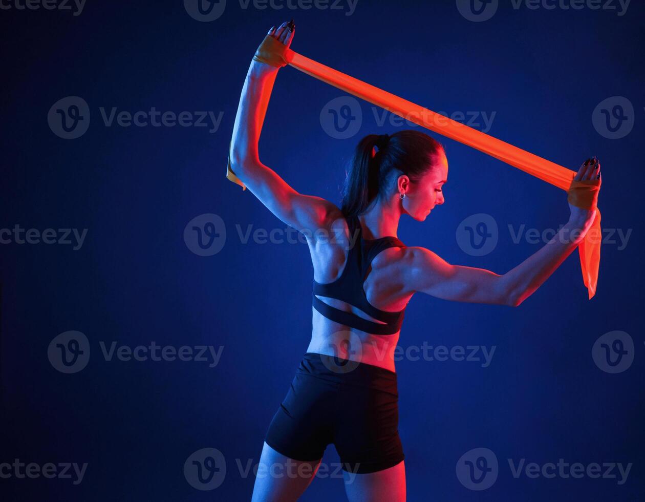 Beautiful ,muscula,r woman is indoors in the studio with neon lighting photo