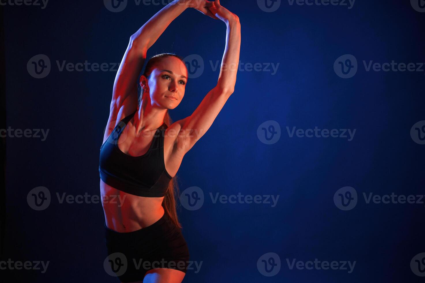 Warm ,up exercises.. Beautiful muscular woman is indoors in the studio with neon lighting photo