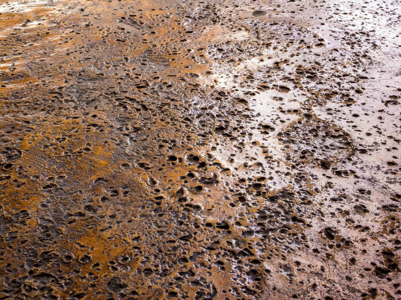 The rugged holes on the rusty color concrete floor photo