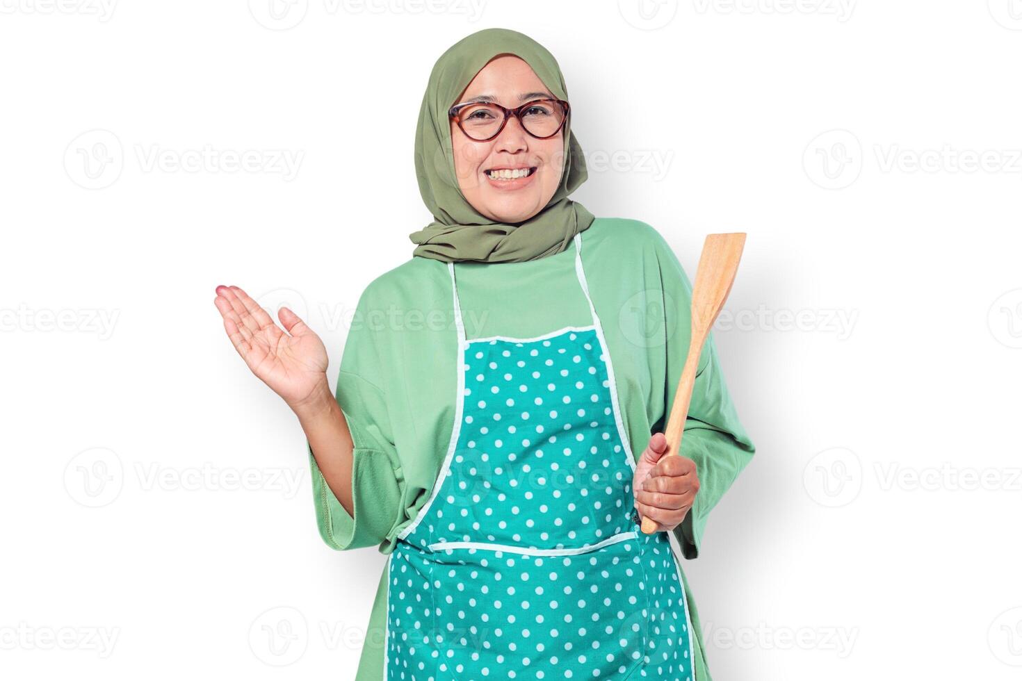 Happy Muslim woman chef in an apron holding a wooden spatula, ready to cook photo