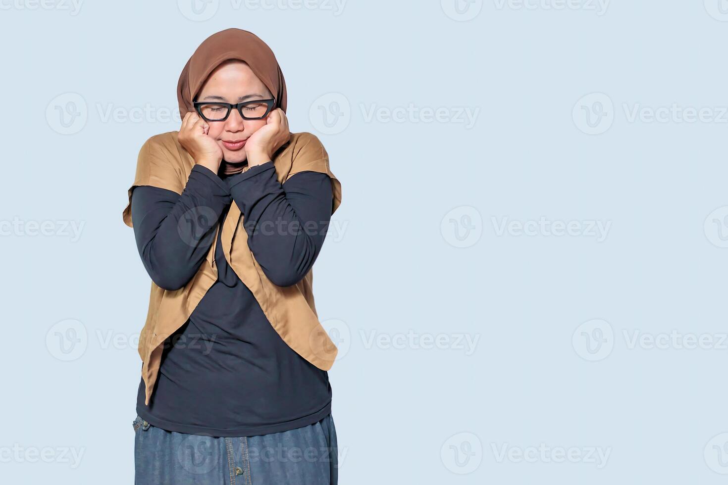 A shy Muslim woman wearing a hijab and glasses, posing with a pensive expression photo