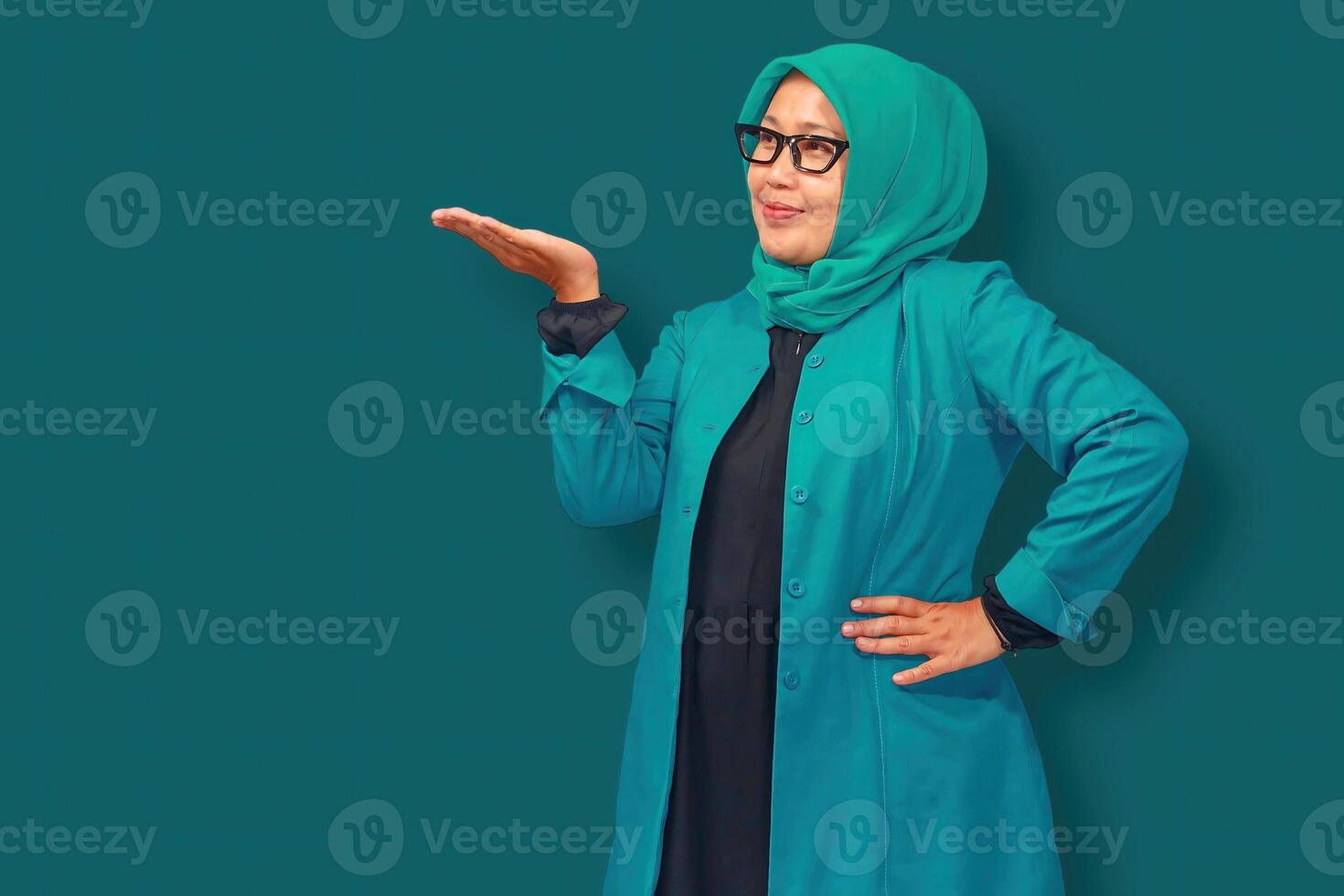 A confident Muslim businesswoman wearing a stylish green hijab and blazer, presenting with an open hand gesture. Perfect for concepts of leadership, professionalism, and career success photo
