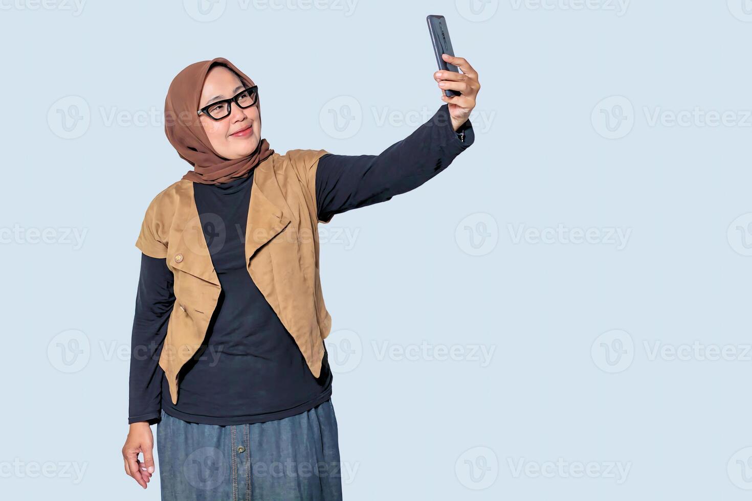 A confident Muslim woman wearing a hijab taking a selfie with her smartphone, expressing joy and modern lifestyle photo