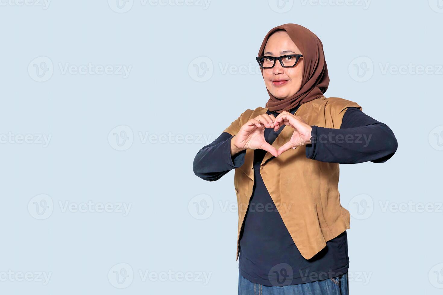 Smiling Muslim woman making a heart shape with hands expressing love and positivity photo