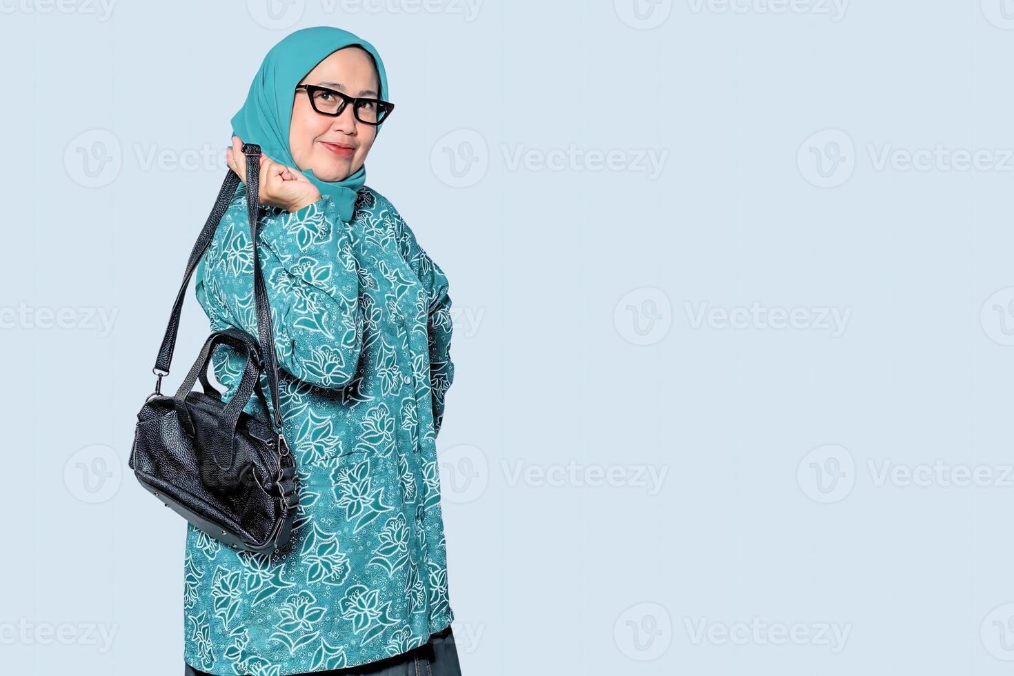 A confident Muslim woman holding a handbag, posing elegantly with charm photo