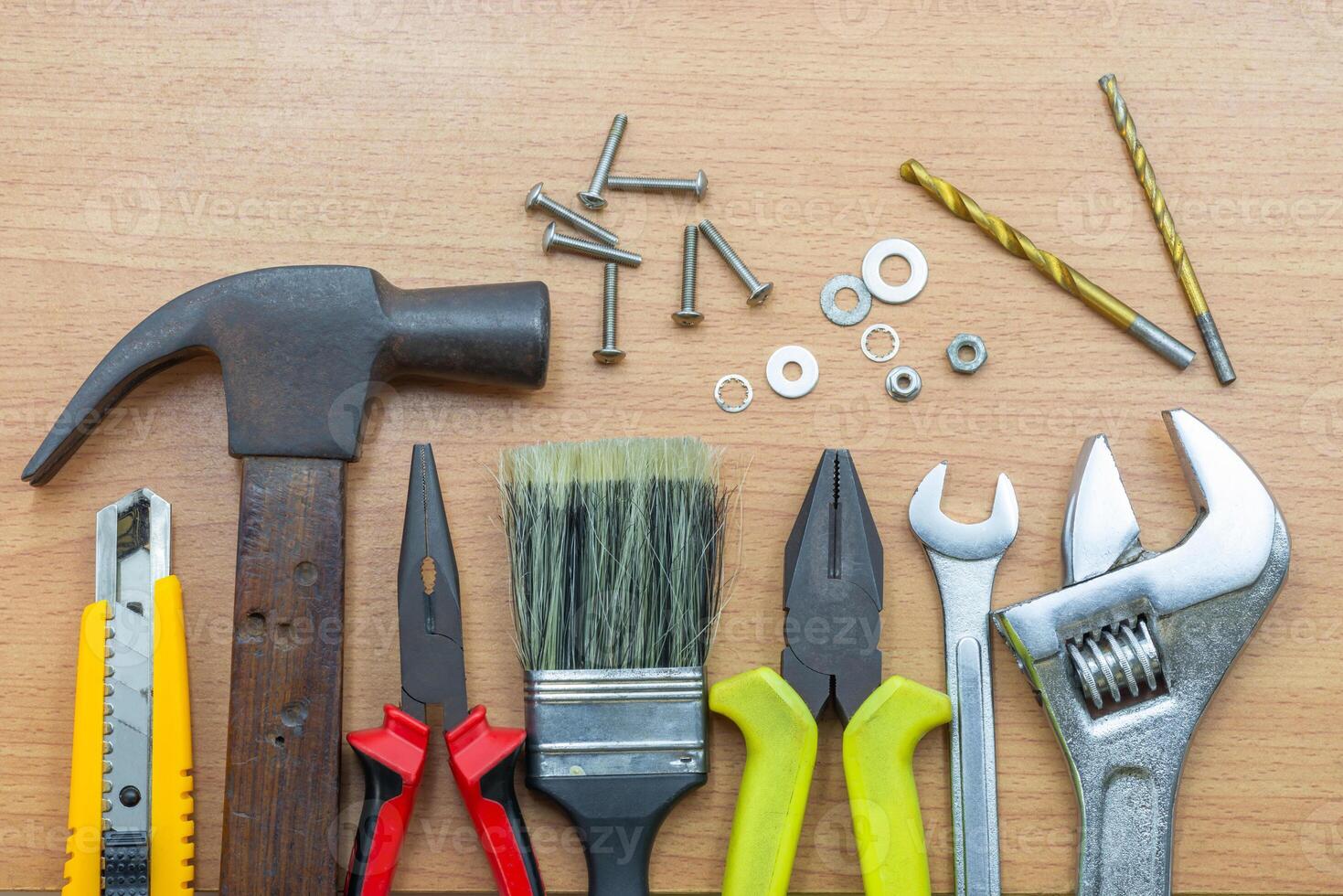 Collection of various used hand tools organized on a wooden surface for construction tasks photo
