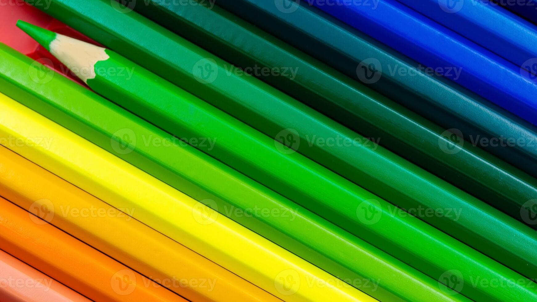 Colorful pencil crayons aligned diagonally with focus on one green pencil photo