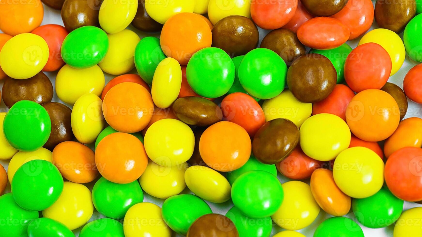 Colorful assortment of hard shelled candies piled together on a white surface photo