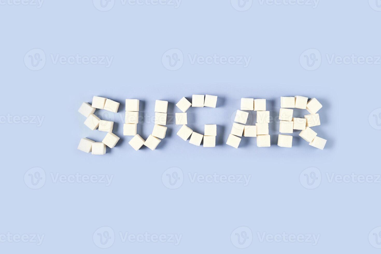 Arrangement of white sugar cubes forming the word 'sugar' on light blue background. photo