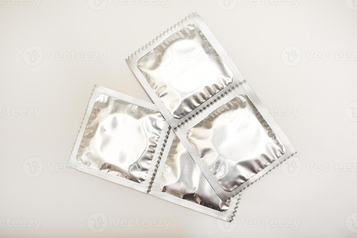 Glossy male prophylactics on a white backdrop. Reflective contraceptive packaging. photo