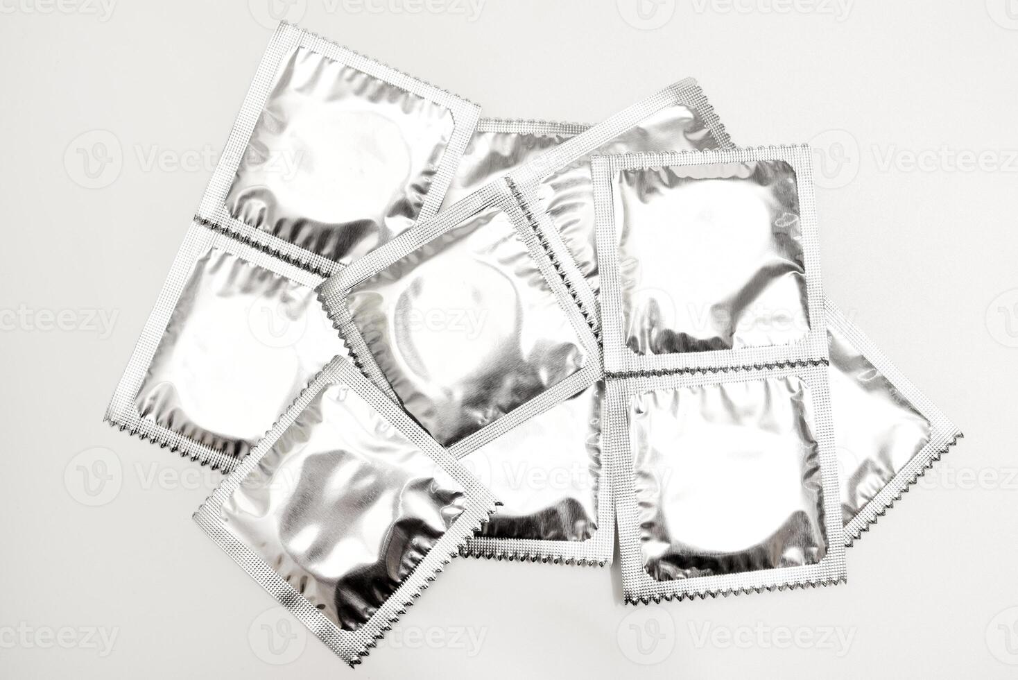 Shimmering birth control products for men in reflective packs on white. Male prophylactics. photo