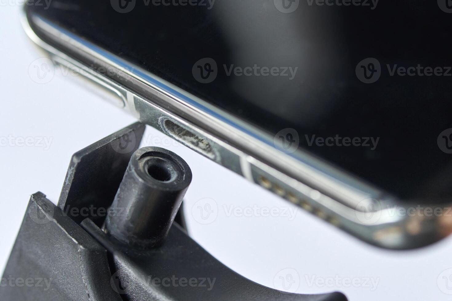 Close up shot of smartphone with visible dirt in charging port on white background. photo