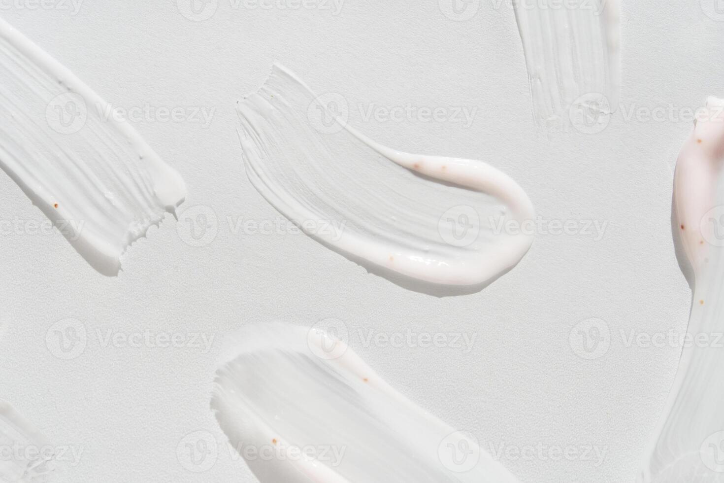 Smooth white cream smears on light background highlighting texture and skincare elements. photo