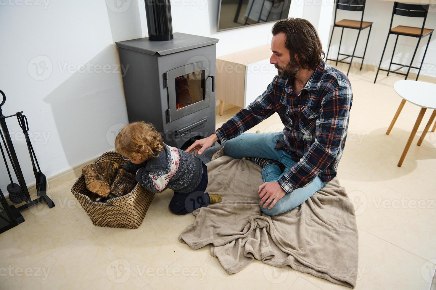 Father and Child Adding Logs to a Potbelly Stove in a Comfortable Home photo
