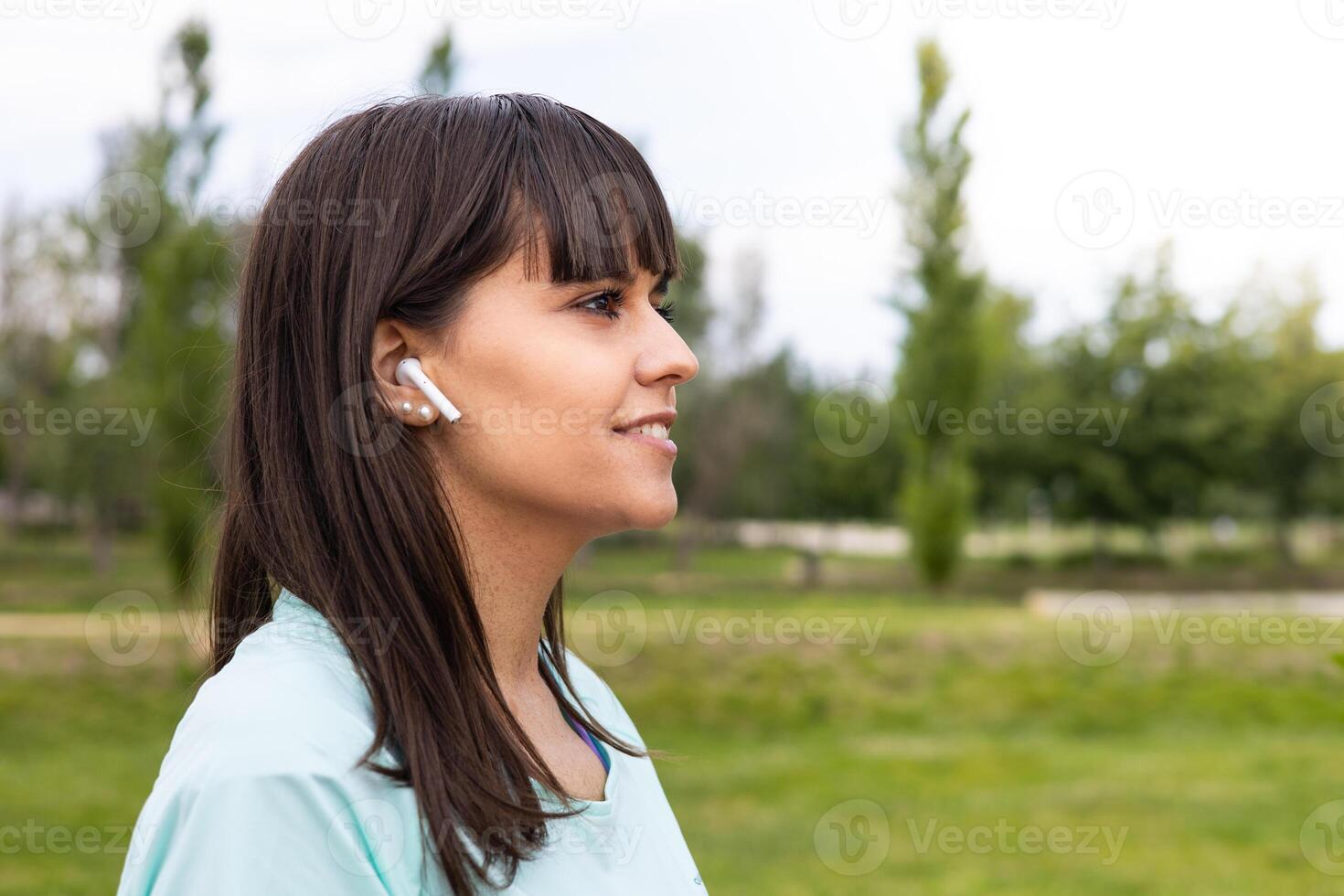 A woman wearing ear buds in a park. photo