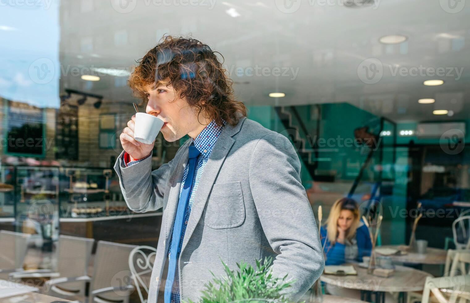 A man in a suit drinking coffee from a cup photo