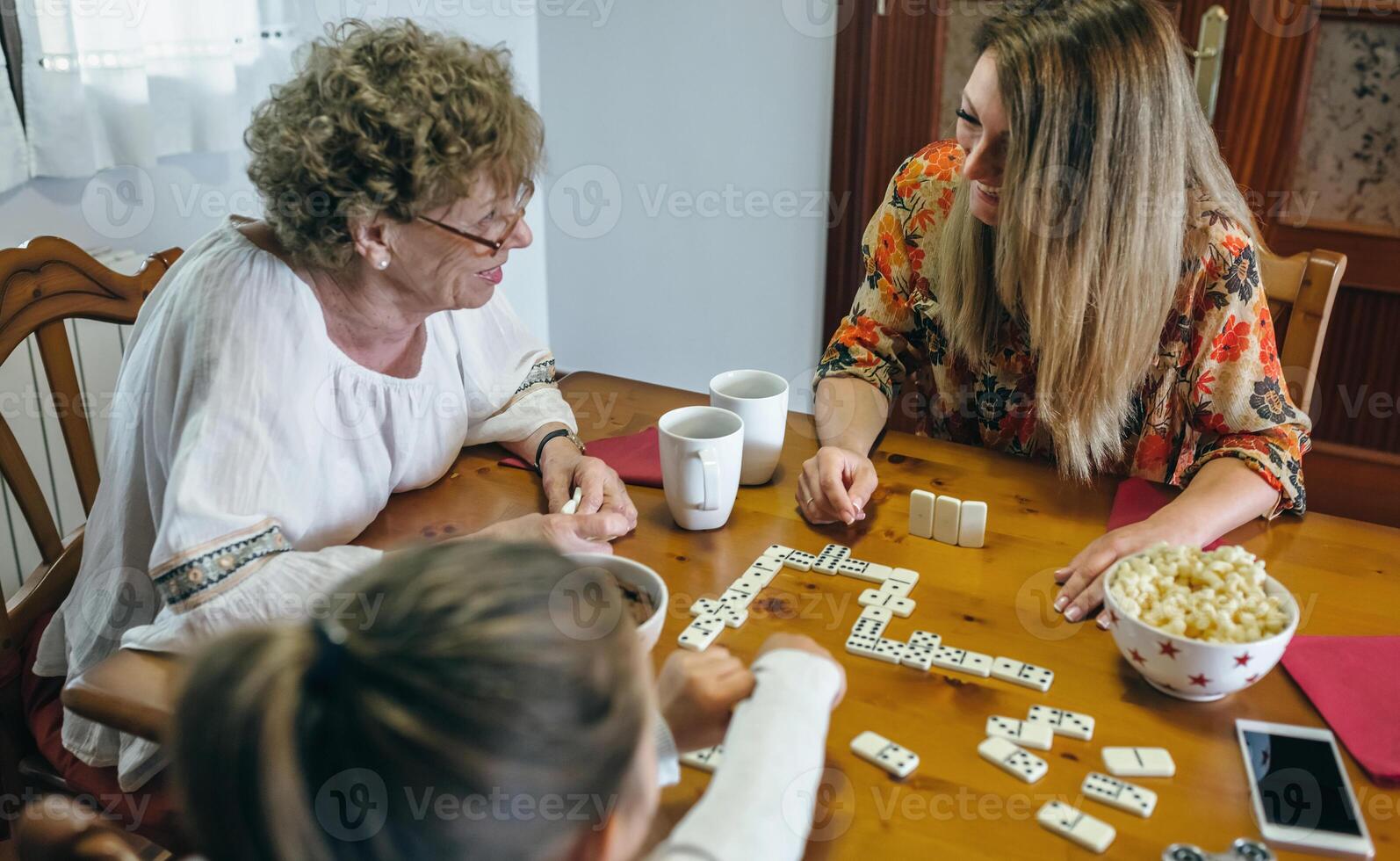 An elderly woman playing a board game with her family photo