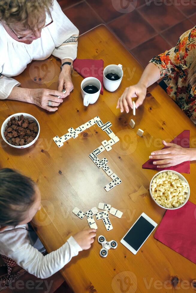Three people playing dominoes at a table photo