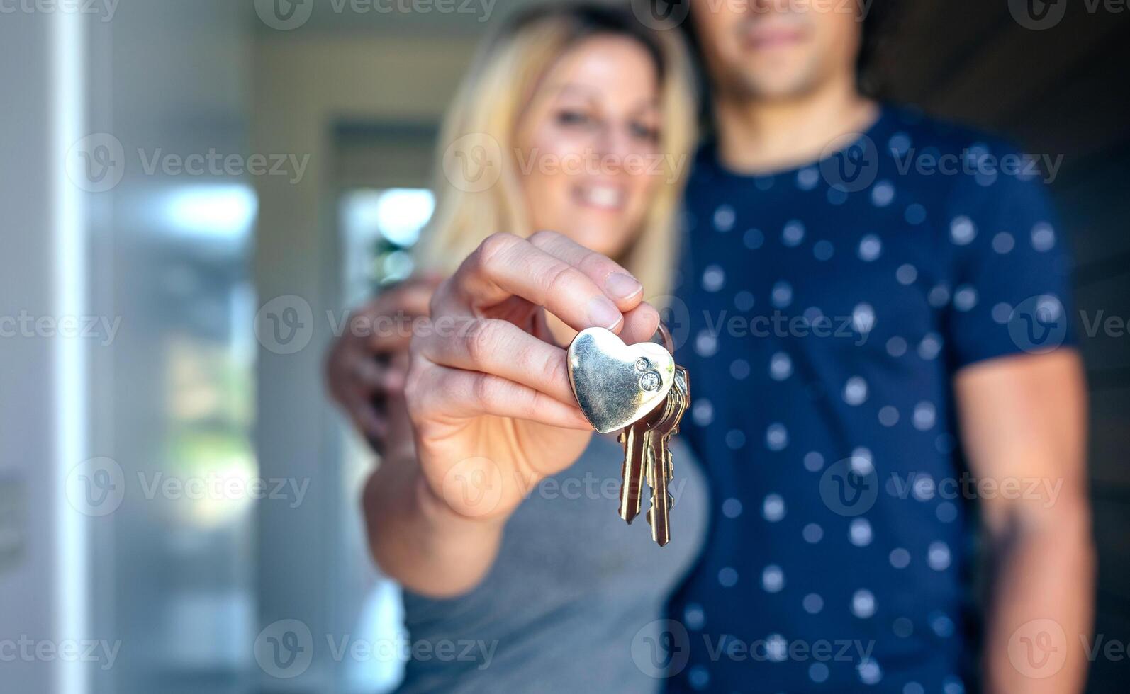 A man and woman holding keys in front of a house photo