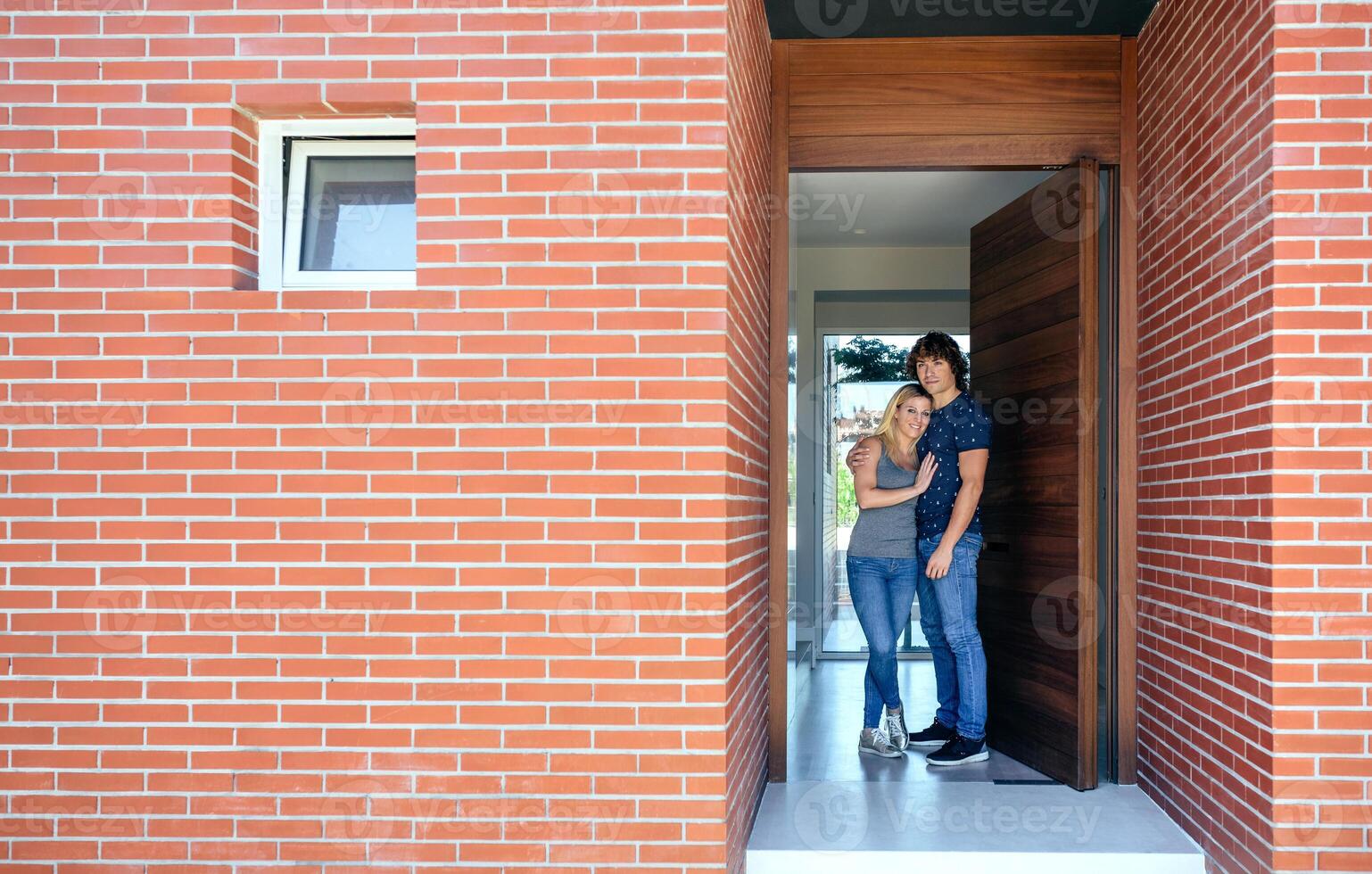 A man and woman standing in front of a brick house photo
