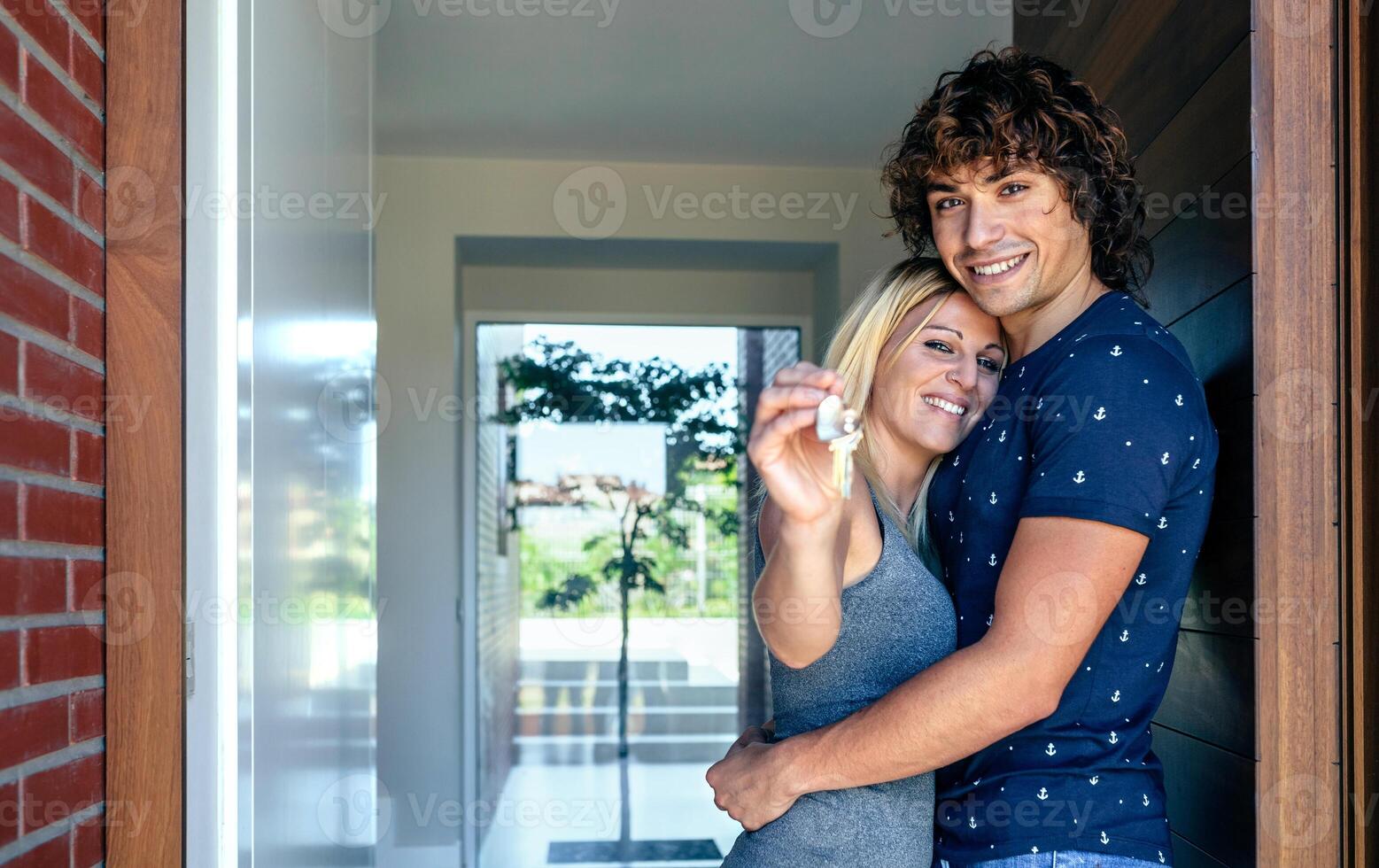 A couple is standing in front of a door holding a key photo