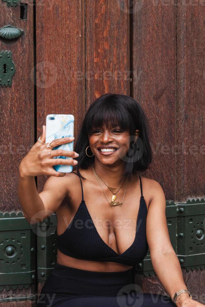 A woman in a black bra top and black skirt taking a selfie photo
