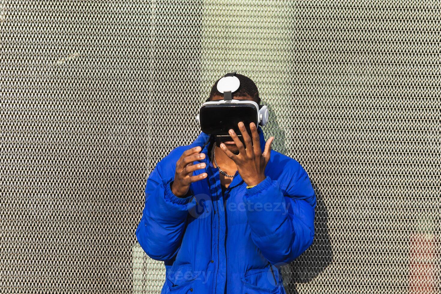 A man wearing a blue jacket and holding a virtual reality headset. An adult man playing virtual game photo