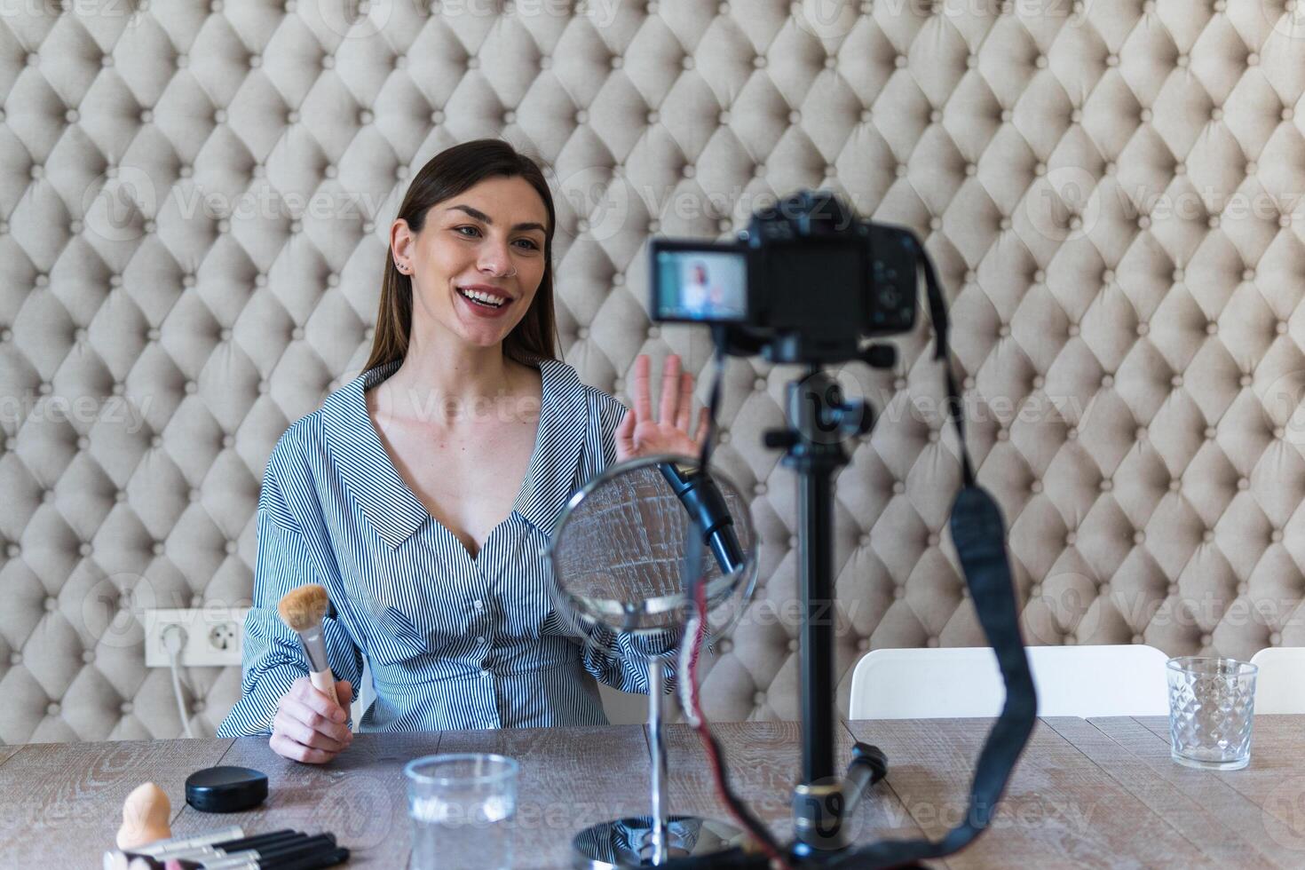 A woman is sitting at a table with a camera and a microphone photo