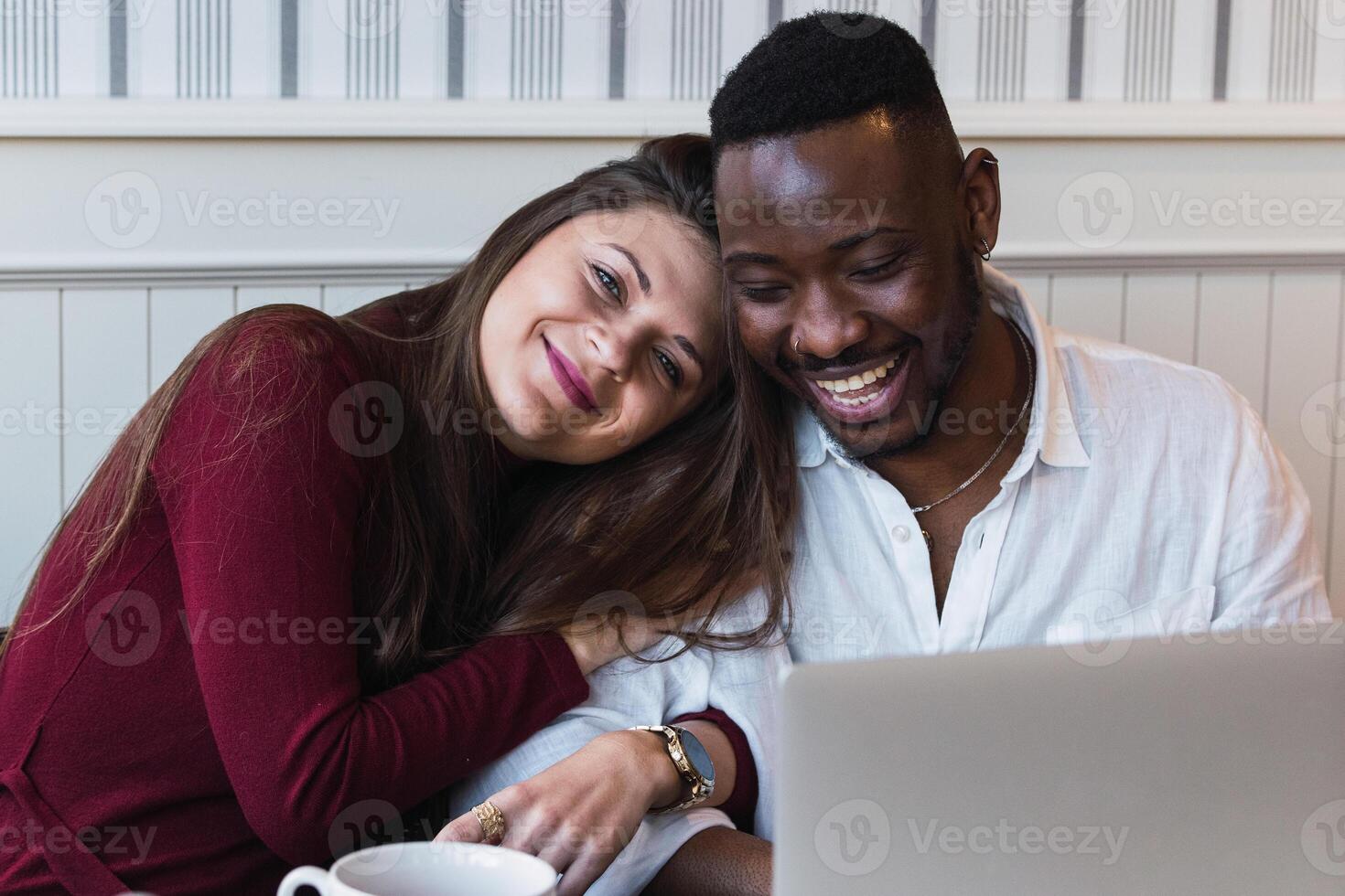A man and woman are smiling while sitting in front of a laptop photo