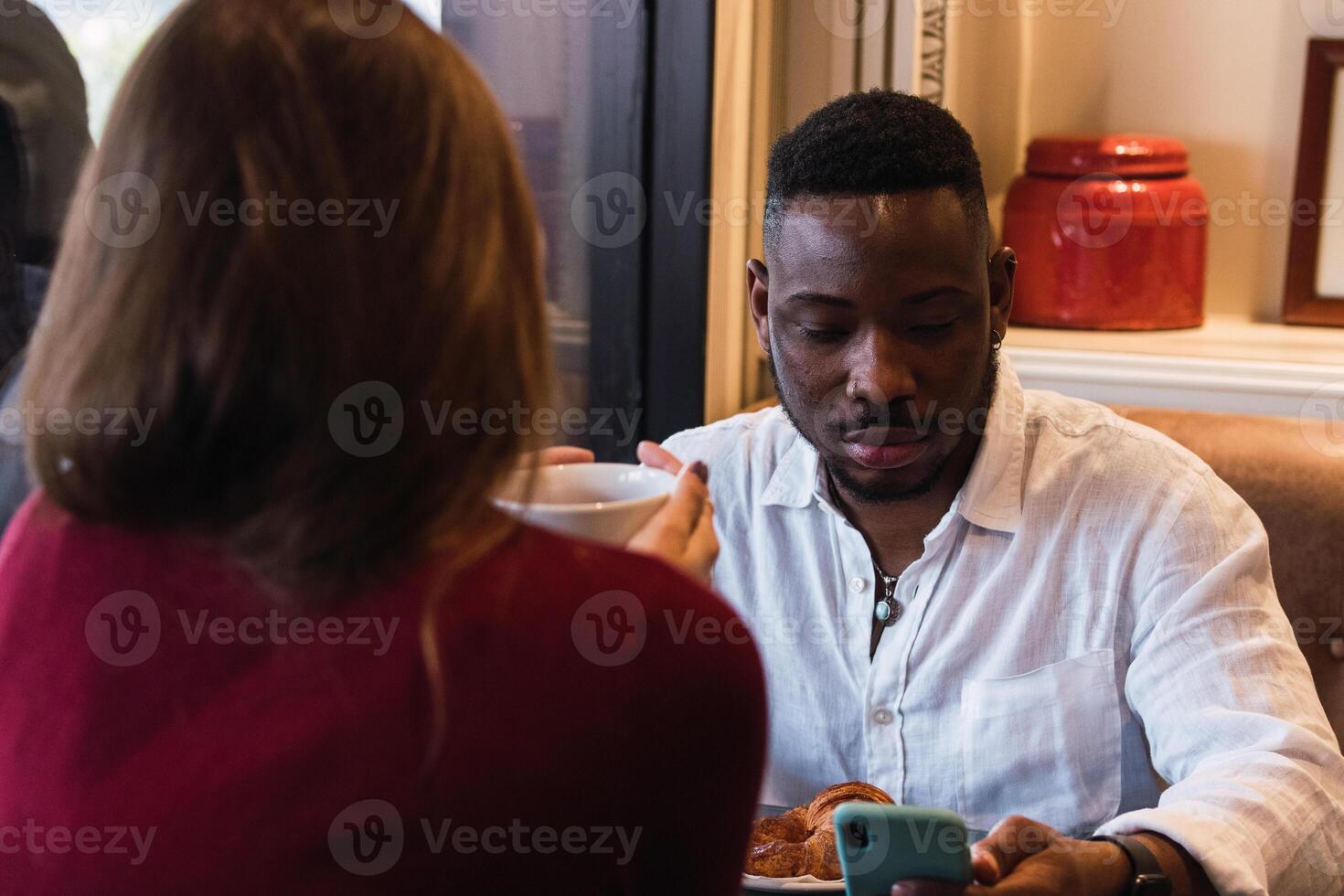 A man and woman sitting at a table with a cell phone photo