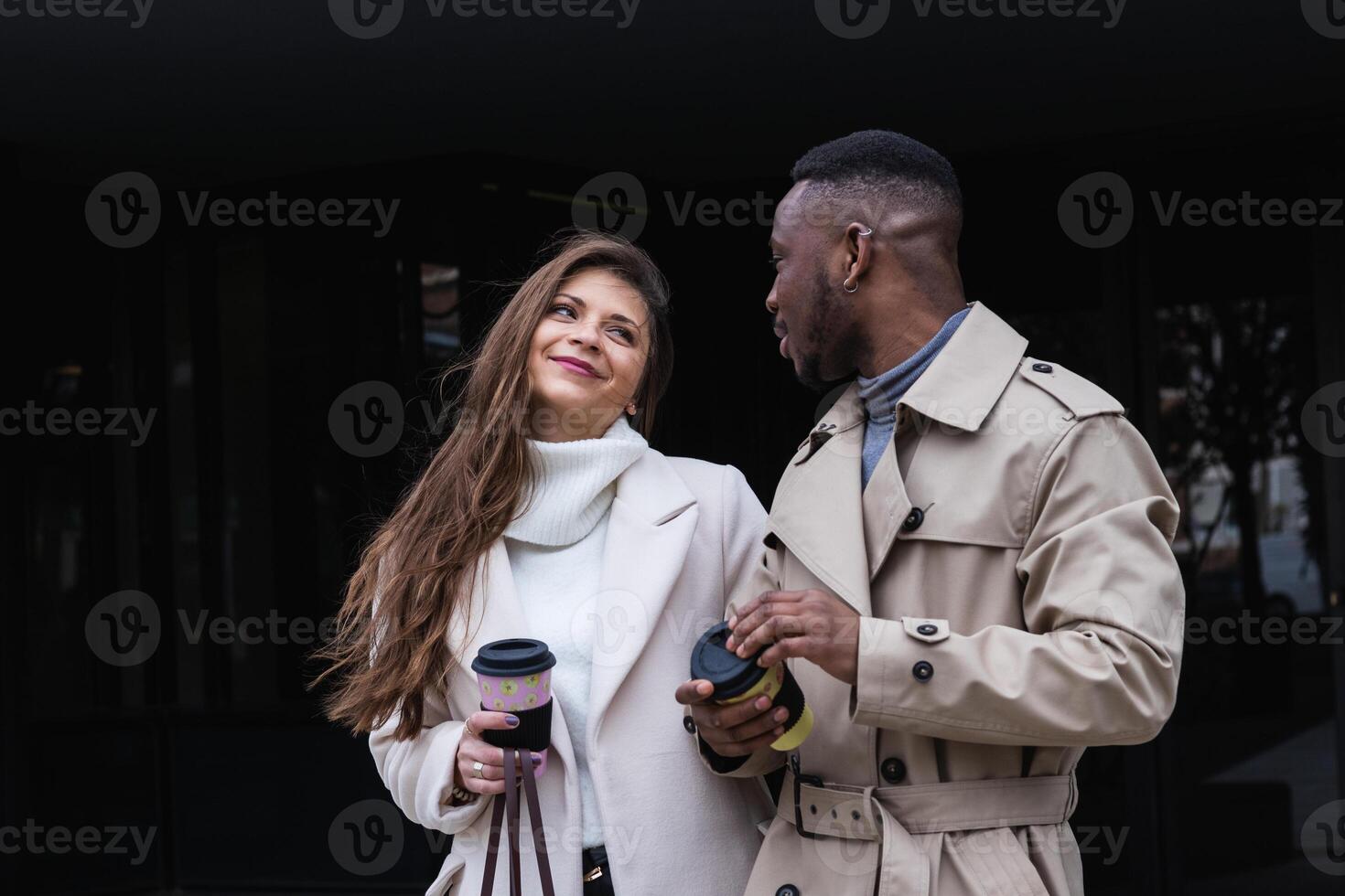 A man and woman in trench coats standing outside photo