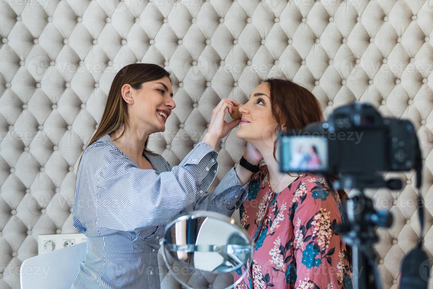 Two women are getting makeup done in front of a camera photo