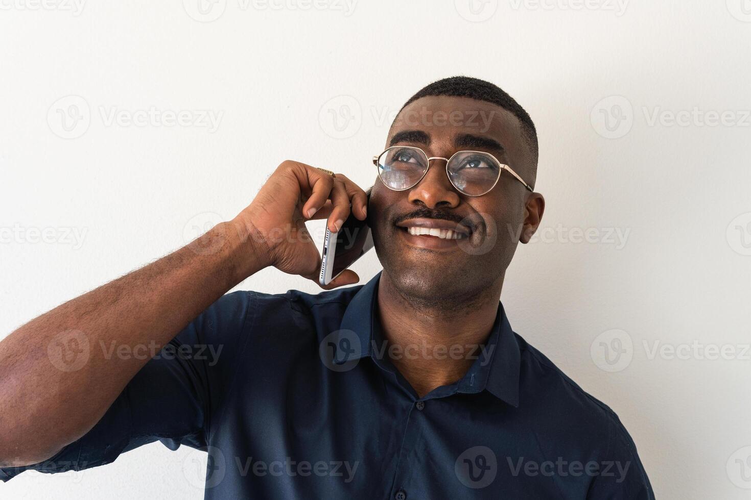 A man in glasses and a blue shirt is talking on a cell phone photo