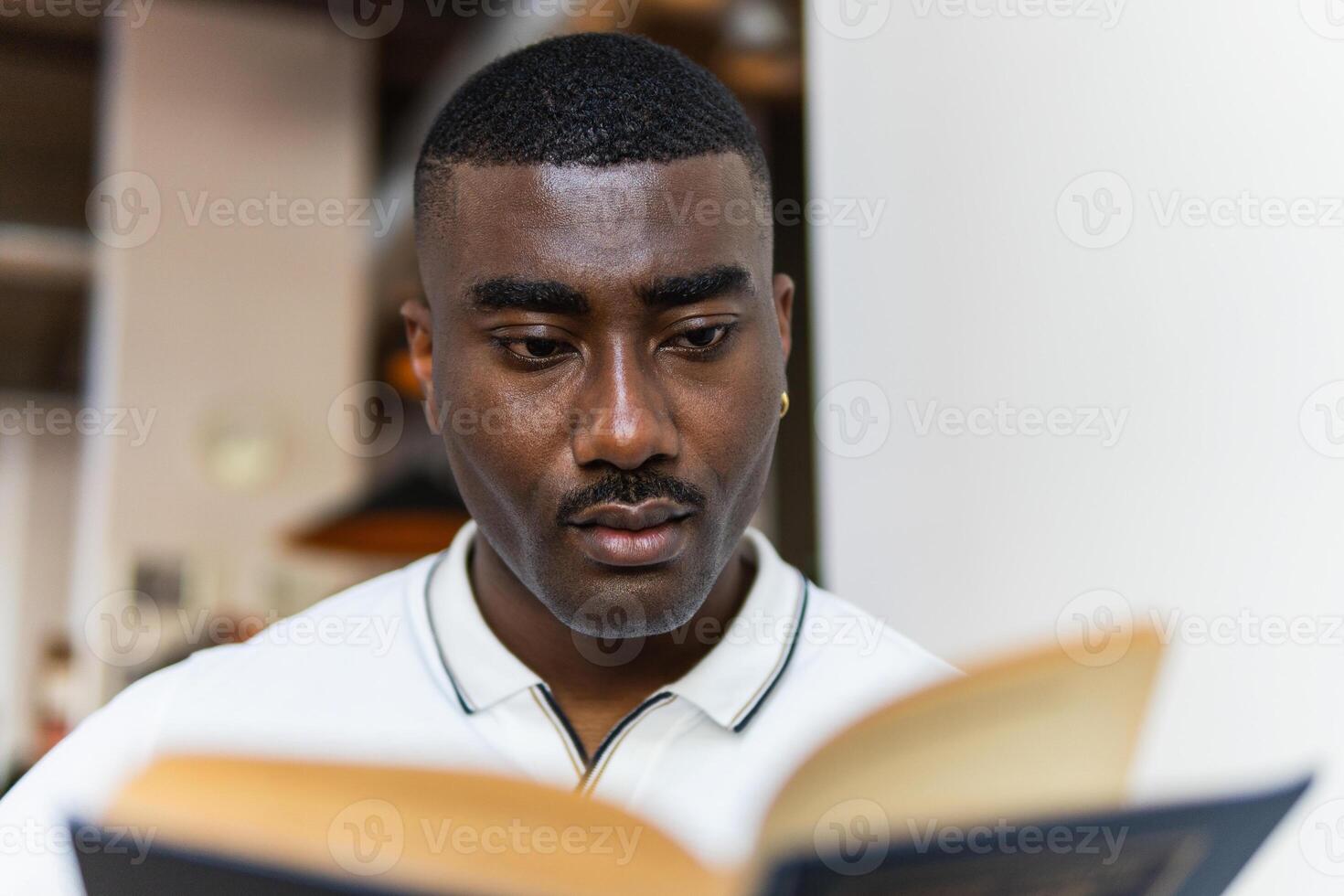 A man is reading a book while looking at the camera photo
