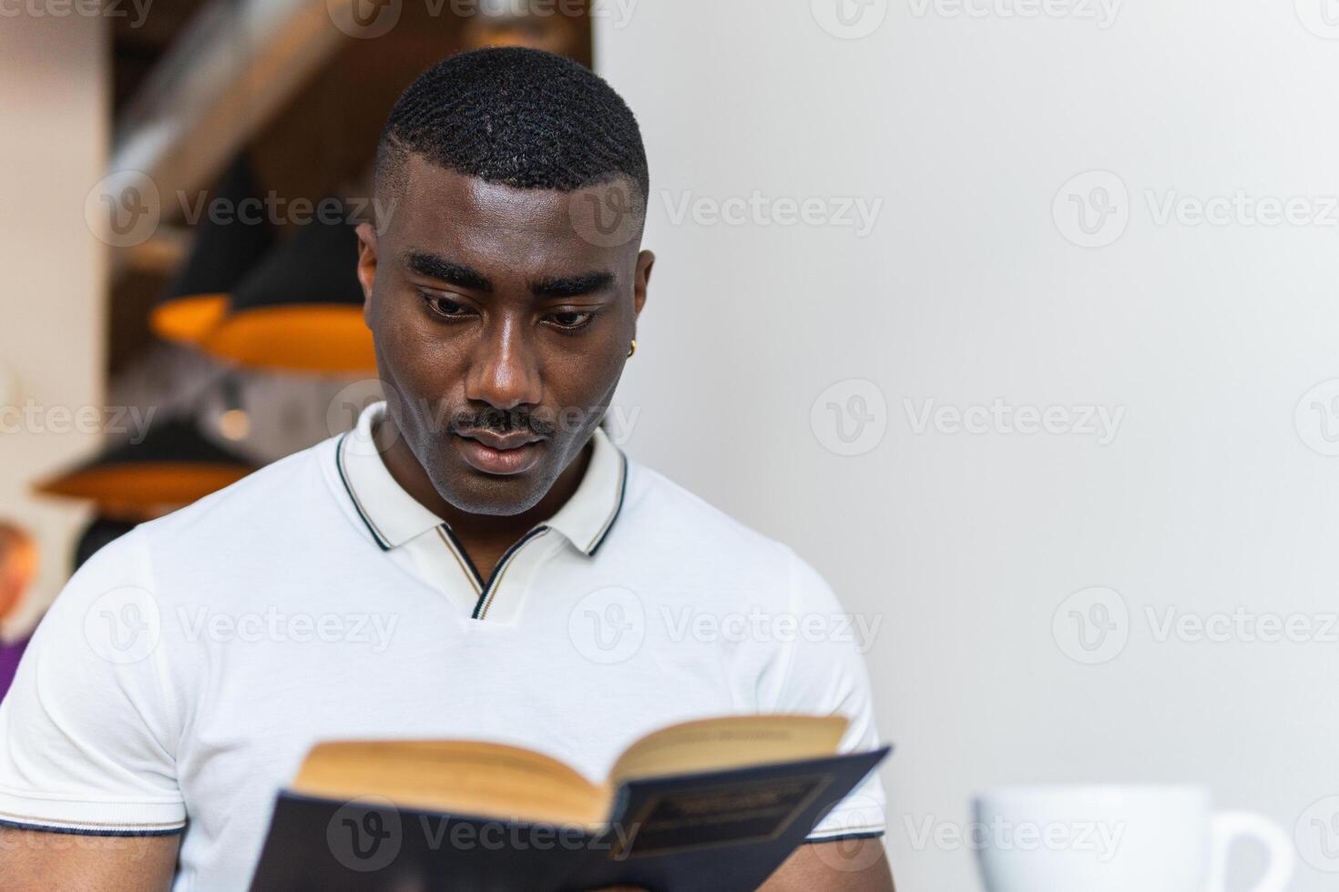 A man reading a book while sitting at a table photo