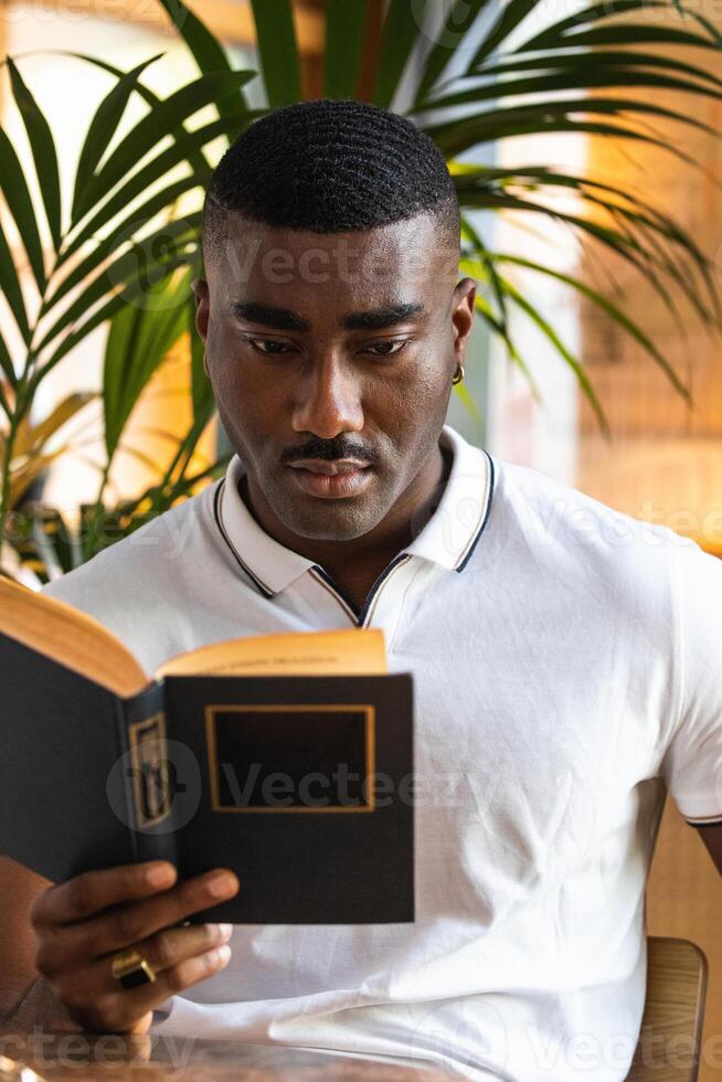 A man is reading a book while sitting at a table photo