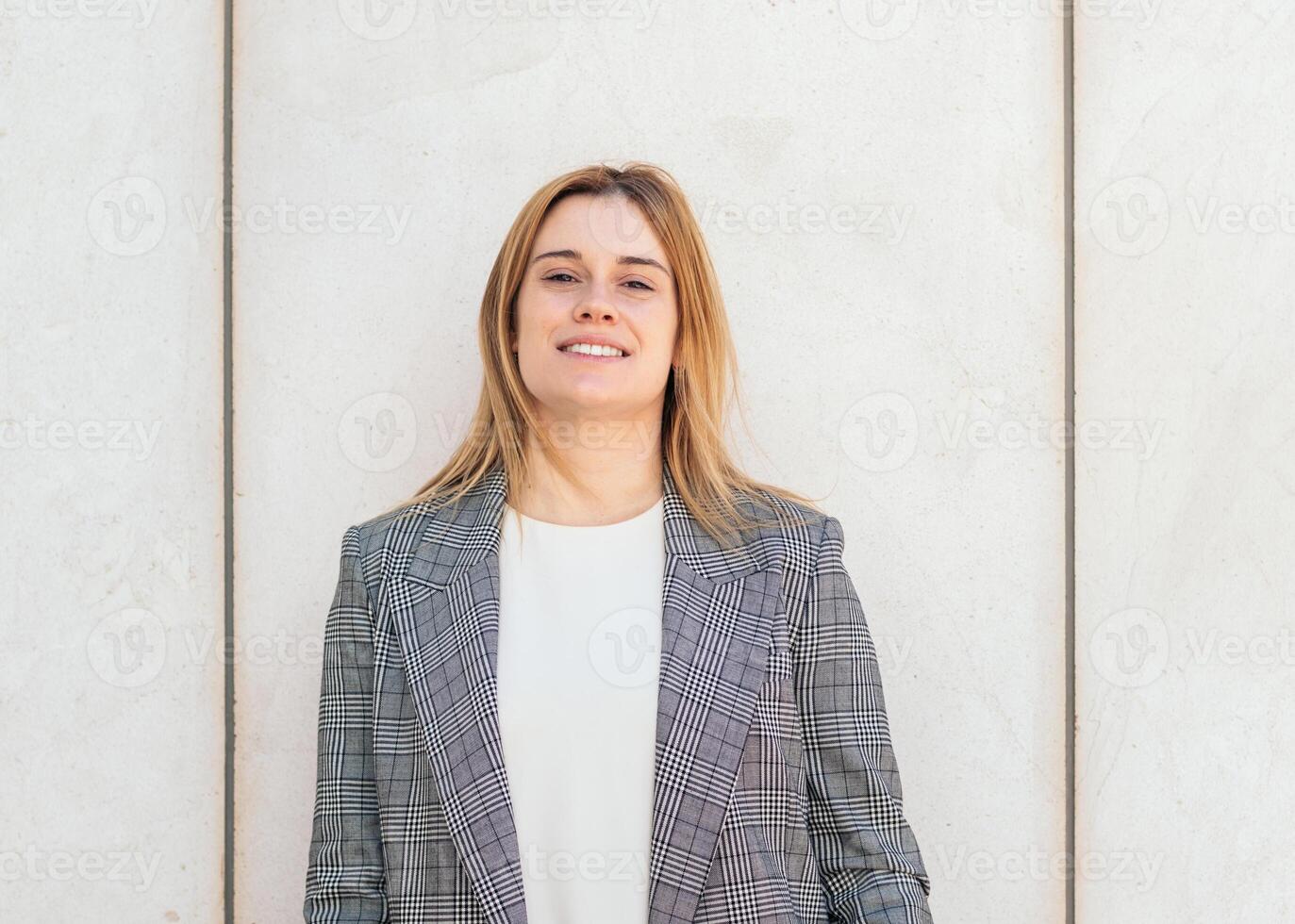 A woman in a suit standing in front of a wall photo