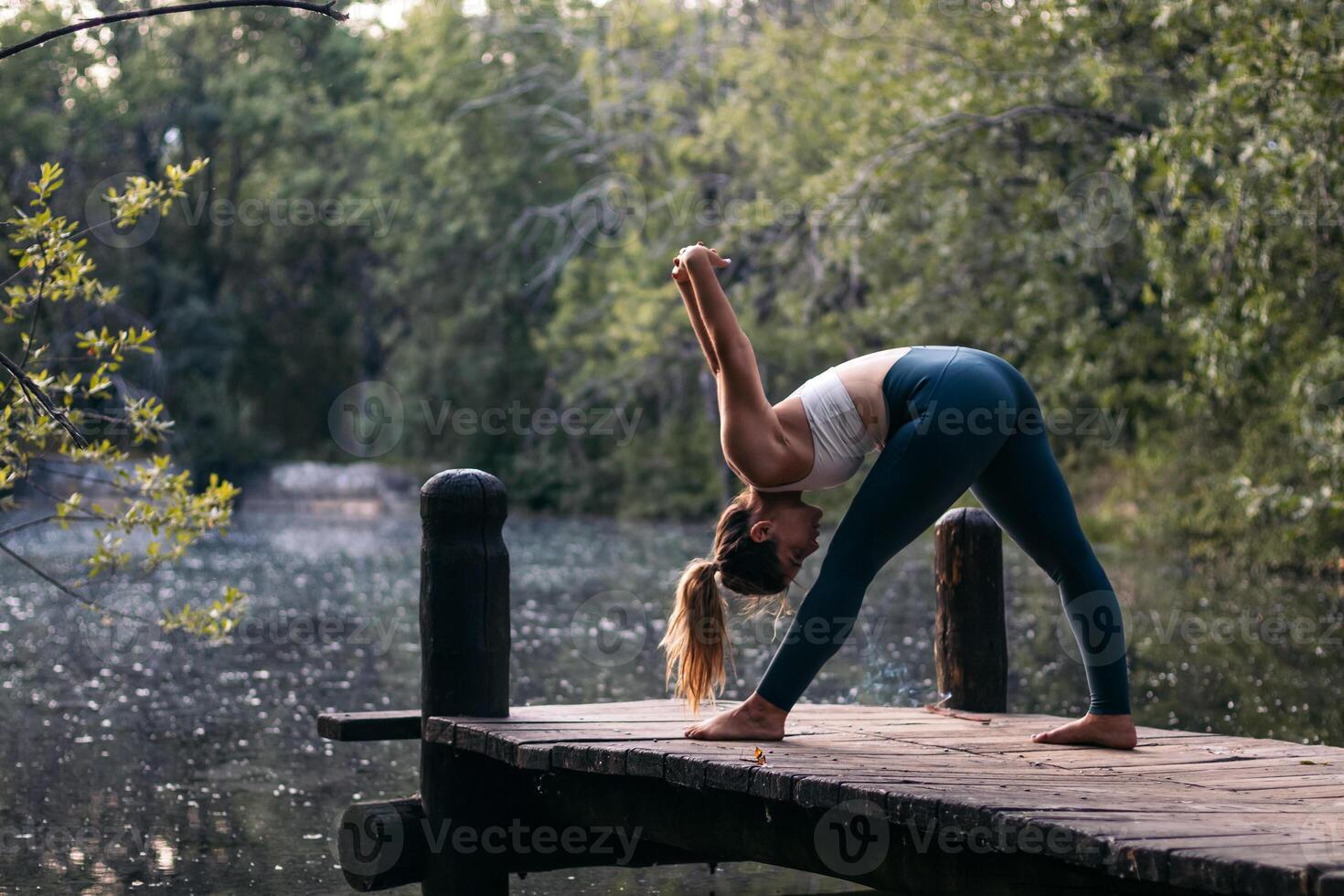 A woman in yoga pants is standing on a dock photo