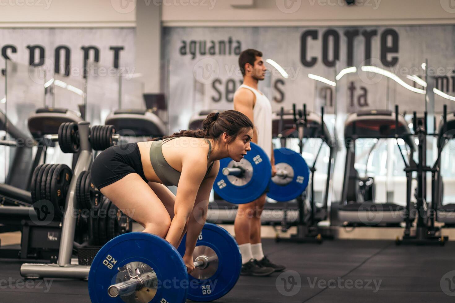 A man and woman in a gym with a barbell photo