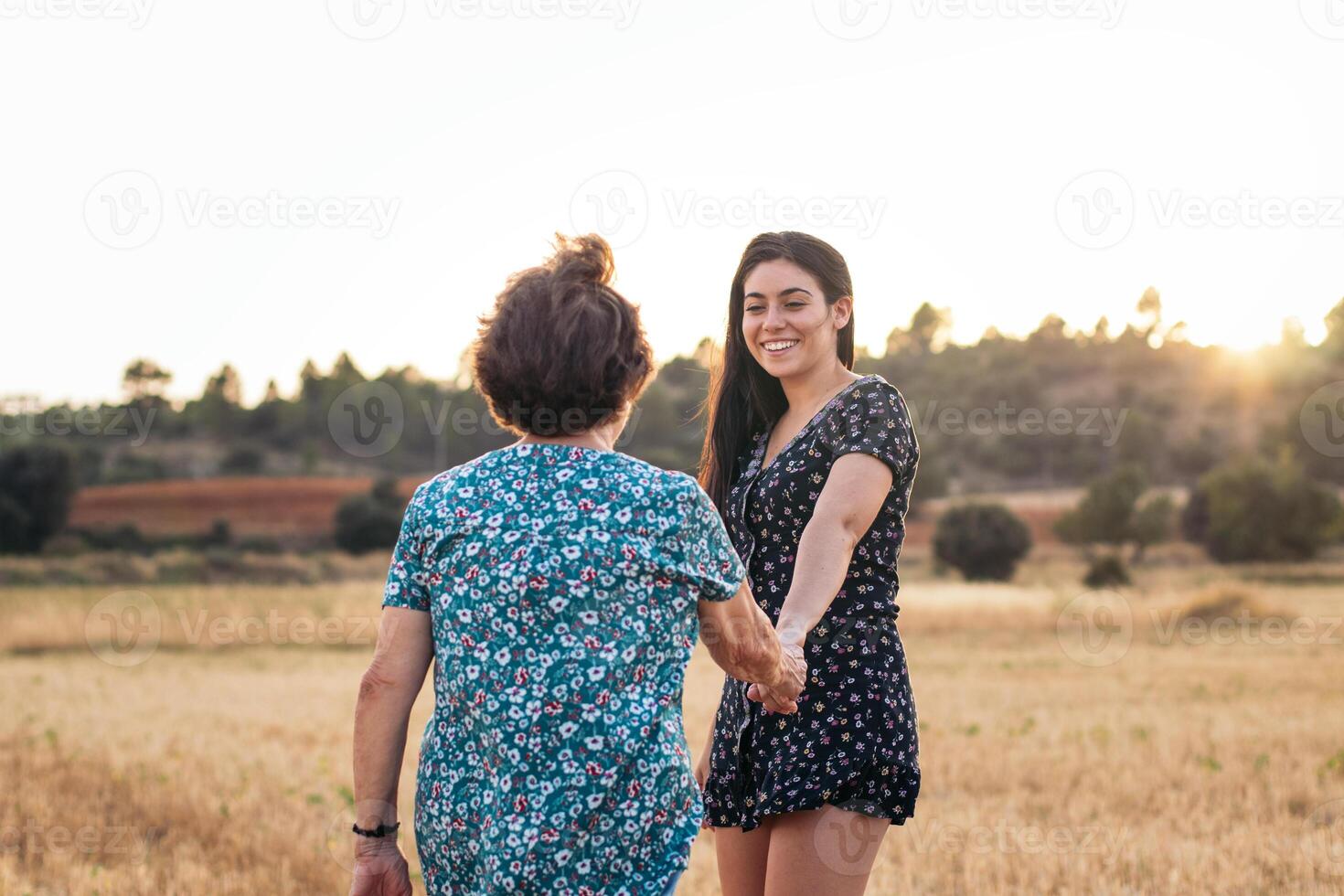 Two women holding hands in a field photo